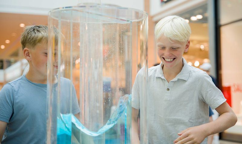 Junge steht vor einem großen Glas Wasser.